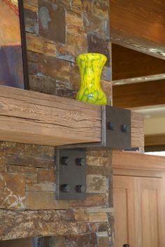 a yellow vase sitting on top of a wooden shelf in front of a brick wall