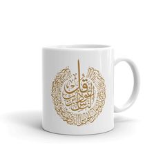 a white coffee mug with arabic writing on the side and gold foil lettering in it