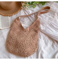 a crocheted bag sitting on top of a bed next to an open book