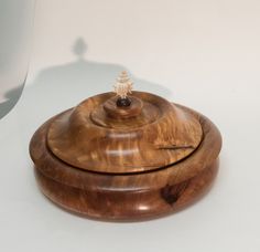 a small wooden bowl with a lid on it's side sitting on a white surface