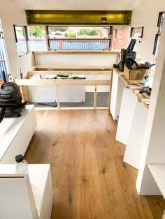 the inside of a camper with wood flooring and white walls, windows, and cabinets