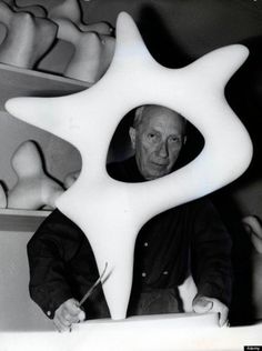 an older man sitting in front of a large white object with two hands on it