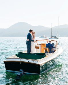 a bride and groom standing on the back of a boat