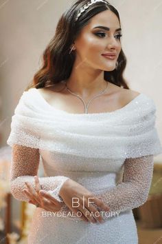 a woman wearing a white wedding dress with long sleeves and beading on the shoulders