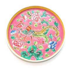 a pink and yellow plate with floral designs on the bottom, sitting on a white surface