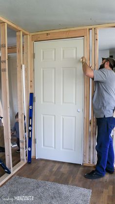 a man standing in front of a white door with tools on the floor next to it