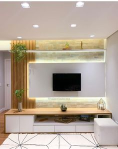 a living room with white furniture and a flat screen tv mounted on the wall above it