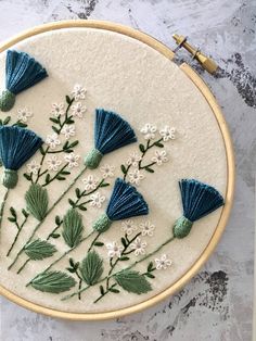 a close up of a embroidery on a hoop with flowers and leaves in the middle