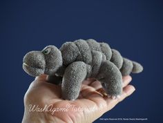 a small stuffed caterpillar is held in someone's hand on a blue background