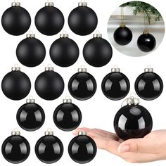 twelve black christmas ornaments hanging from the ceiling and being held by someone's hand