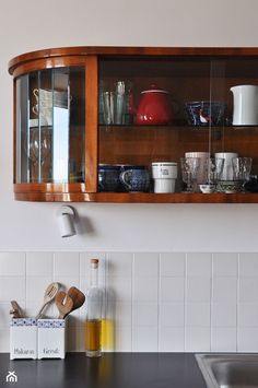 a wooden shelf above a kitchen sink filled with dishes and utensils on it