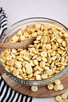 a glass bowl filled with peanuts on top of a wooden cutting board next to a striped towel