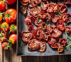 tomatoes and herbs on a tray next to a wooden table