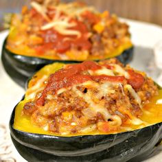 three stuffed eggplant halves on a plate with cheese and sauce in the middle