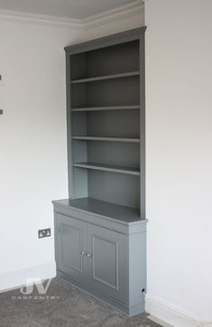 an empty bookcase in the corner of a room with carpeted floor and white walls