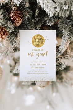 a white and gold new year's eve party card hanging from a christmas tree