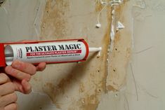 a hand holding a white paint can with the words plaster magic on it