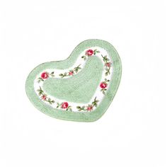 a green heart shaped rug with roses on the front and bottom, sitting on a white surface