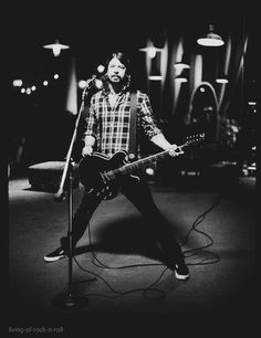 a man standing in front of a microphone while holding a guitar