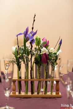 flowers are in vases on a table with wine glasses and place settings for the guests