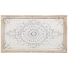 an ornate white wall hanging on the side of a wooden frame, with intricate designs