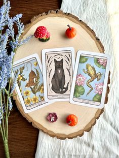 three tarot cards sitting on top of a wooden table next to flowers and fruit