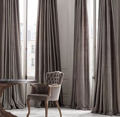 a chair sitting in front of a window covered in gold drapes and draperies