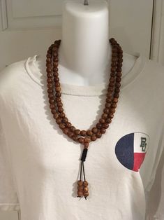 "Bodhi seed mala necklace made of 108 12mm beads with a Bodhi seed guru bead and an adjustable knot that allows you to change the length and tightness of the beads. Bodhi seeds are usually not polished so they are a solid color with small ridges or veins. Bodhi in Sanskrit translates to \"enlightened\" or \"awakened,\" therefore the Bodhi seed means \"enlightened seed.\" Bodhi is also a term in Buddhism to reflect a Buddha's understanding of the true nature of things. Many Buddhist wear the Bodh