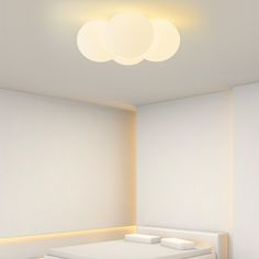 there is a white bed in the corner of this room with three round lights above it