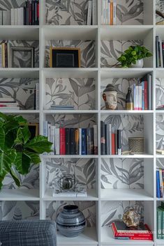 a bookshelf filled with lots of books next to a potted green plant