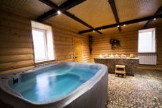 an indoor hot tub in the middle of a room with stone flooring and wooden walls