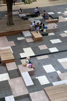 people are sitting on benches in the middle of an open area with tiled flooring