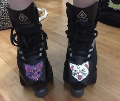 a pair of shoes with cats painted on the upper part of each shoe, sitting on top of a hard wood floor