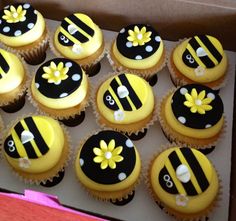 cupcakes decorated with yellow and black frosting are in a box on the table