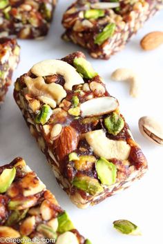 several pieces of fruit and nut bars on a white surface with nuts scattered around them