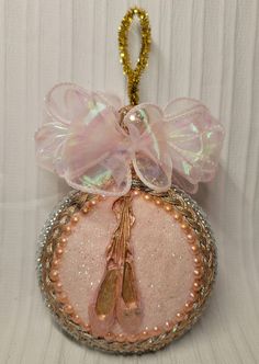 a pink ornament hanging from a gold chain on a white background with sequins