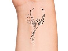 a small bird tattoo on the back of a woman's left arm and wrist