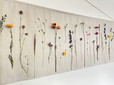 an arrangement of flowers are displayed on a white wall hanging from the side of a building