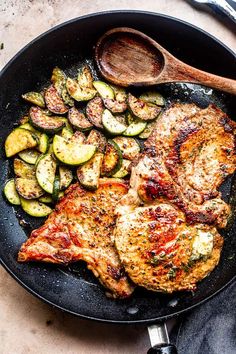 meat and vegetables cooking in a skillet with a wooden spatula on the side