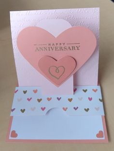 a card with two hearts on it and the words happy anniversary written in gold foil