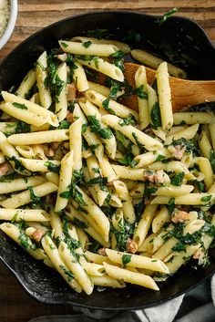 a skillet filled with pasta and spinach