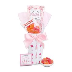 a white box filled with gummy bears next to a pink ribbon and greeting card