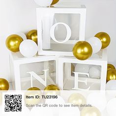 some white and gold balloons are in the shape of cubes with numbers on them