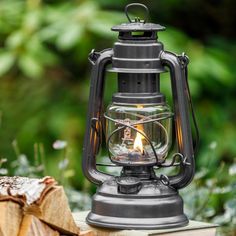 an old fashioned lantern sitting on top of a piece of wood