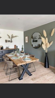 a dining room table with plates and bowls on it, in front of a mirror