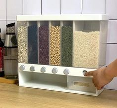 a person holding a spice rack with spices and grains in it on a counter top