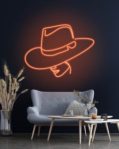 a living room with a couch, coffee table and neon hat wall decal on the wall