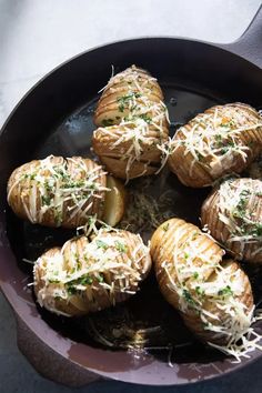 baked potatoes with parmesan cheese and herbs in a frying pan