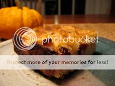 a piece of cake sitting on top of a white plate next to an orange pumpkin