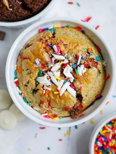 two bowls filled with cake and sprinkles on top of a white table